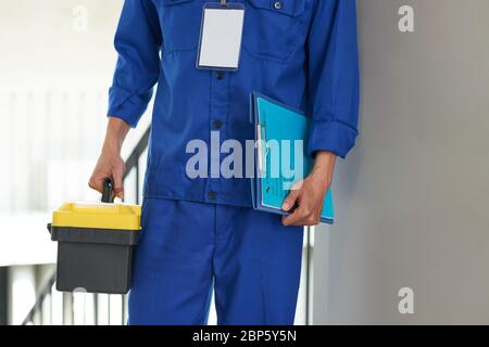 Cropped image of service worker in blue uniform holding contract and toolbox Stock Photo