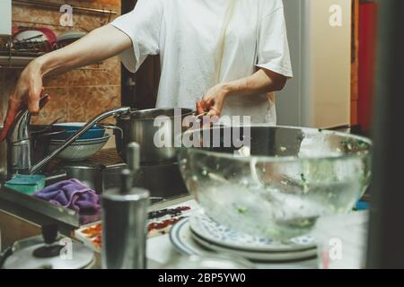 Unrecognizable woman washes dishes in kitchen Stock Photo