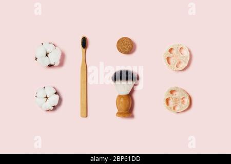 Bathroom accessories on pink background. Natural bamboo toothbrush, sponges, cotton flowers, shaving brush. Flat lay, top view. Stock Photo