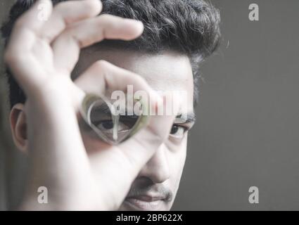 A young man showing dollar in attractive way , stylish view of man face from folded dollar bills. Stock Photo