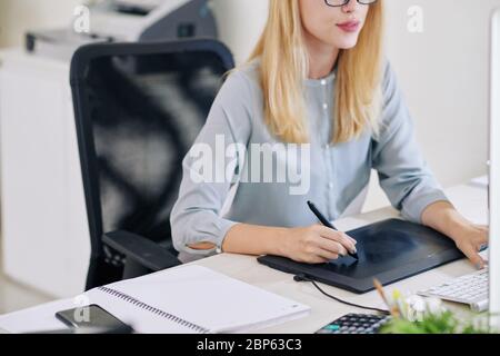 Female graphic designer working on tablet and drawing with stylus Stock Photo