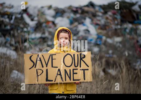 Small child holding placard poster on landfill, environmental pollution concept. Stock Photo