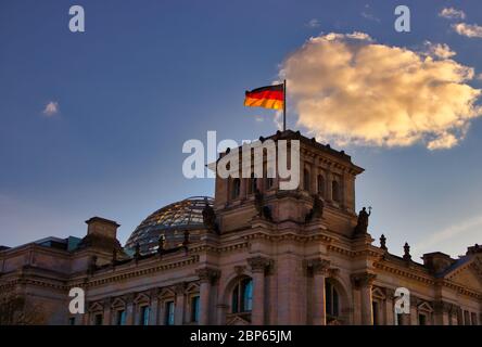 The famous Reichstag building in Berlin, seat of the German Bundestag, with a waving flag of the Federal Republic of Germany Stock Photo
