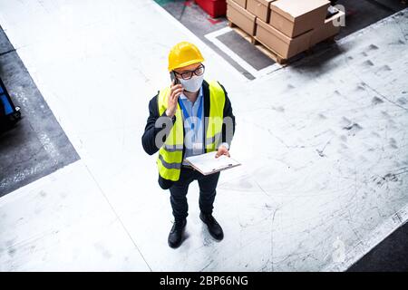 Technician or engineer with protective mask and helmet working in industrial factory. Stock Photo