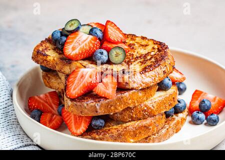 Traditional french toasts with blueberries and strawberries on a white plate. Stock Photo