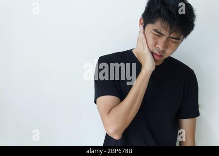young man feeling pain, holding his cheek with hand, suffering from bad toothache. Tooth ache concept. Stock Photo
