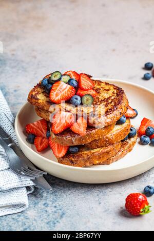 Traditional french toasts with blueberries and strawberries on a white plate. Stock Photo