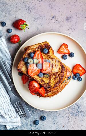 Traditional french toasts with blueberries and strawberries on a white plate. Stock Photo