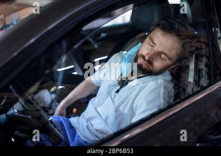 Tired and exhausted doctor sitting in car after long and difficult shift, sleeping. Stock Photo