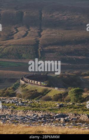 Freightliner class 66 locomotive 66510 running off Ribblehead viaduct with a merry go round coal train with the countryside towering over it