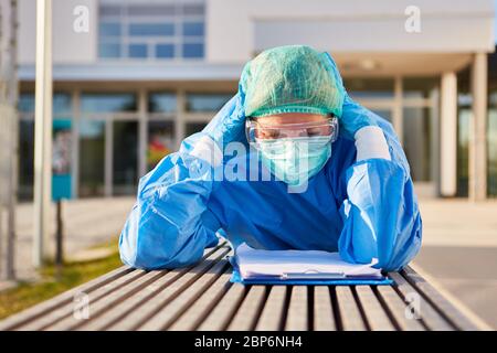 Nursing staff in front of clinic studies thoughtful or exhausted list for contact tracking during the coronavirus Stock Photo