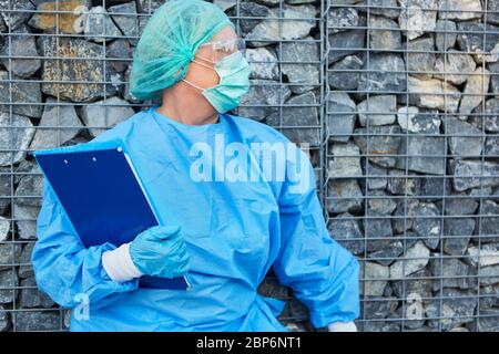 Nursing staff or containment scout awaits visitors with list for contact tracking in coronavirus pandemic Stock Photo