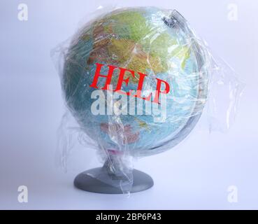 Text Help and model of planet Earth wrapped in polyethylene plastic disposable package on grey background. Ecology, plastic problems. Concept pollution of environment with polyethylene plastic waste World Earth Day, Save the planet Stock Photo