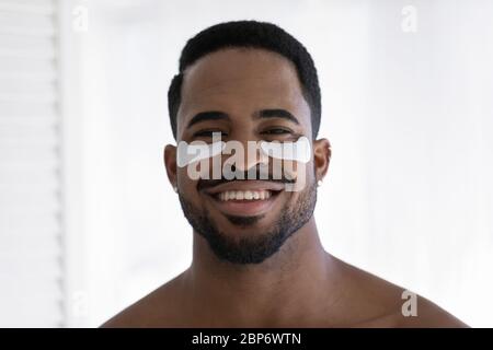 Portrait of smiling biracial man use under eye patches Stock Photo