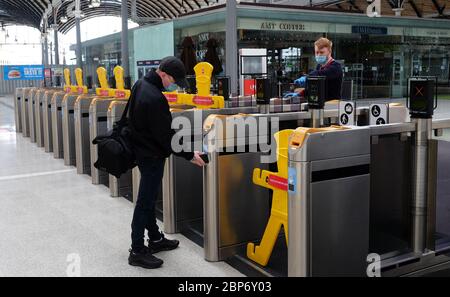 A passenger scans his ticket at barriers that have been blocked for social distancing measures at Newcastle train station, as train services increase as part of the easing of coronavirus lockdown restrictions.