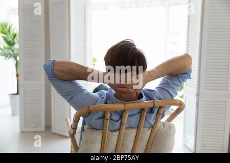 Back view of Caucasian man relax in chair at home Stock Photo