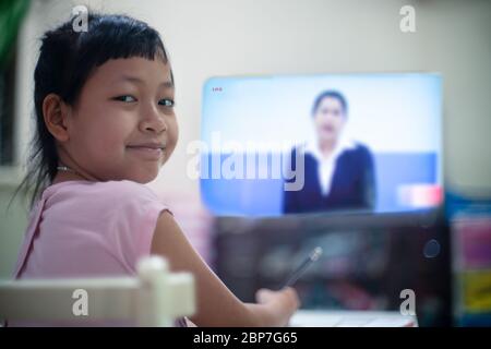 Little child girl learning on DLTV or Distance Learning Television at home,Social distance during quarantine, Online education concept Stock Photo