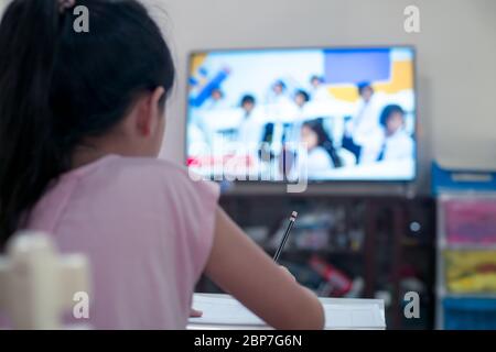 Little child girl learning on DLTV or Distance Learning Television at home,Social distance during quarantine, Online education concept Stock Photo