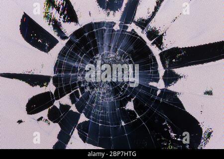 Impact damage on lcd screen, radial cracks, pixel grid leakage and discoloration. Close-up with selective focus. Stock Photo