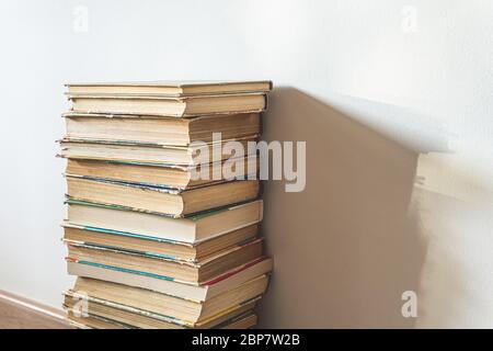 Big stack of old books over white wall, education concept, with copy space Stock Photo