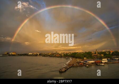 View over Santo Domingo on the island of the Dominican Republic, The Caribbean, West Indies. A full rainbow lights up the stormy sky and clouds Stock Photo