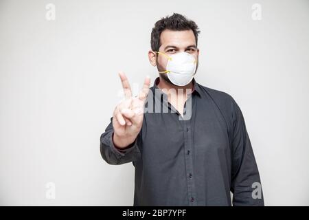Man covering his face with covid-19 mask, safe working environment victory sign Stock Photo