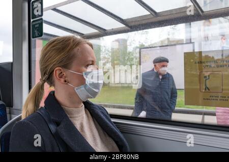 Beautiful girl or woman with mask looking through the window in a bus,  train or metro during Covid or Coronavirus days Stock Photo