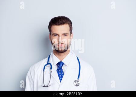 Portrait of handsome serious doctor in white coat and stethoscope on neck isolated on grey background Stock Photo