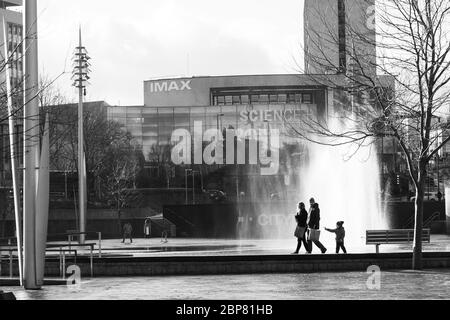 Family walking past water fountains with National Science and Media Museum in the background, Centenary Square, Bradford, West Yorkshire, England, UK. Stock Photo