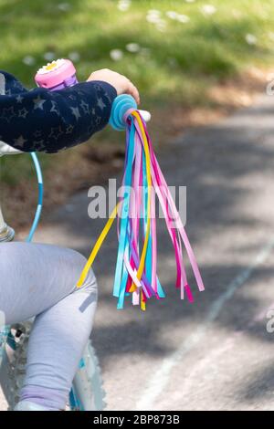 a close up view of bright coloured tassels attached to a little girls bike Stock Photo