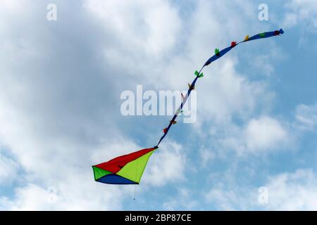 a close up view of a bright coloured kite flying high up in the air Stock Photo