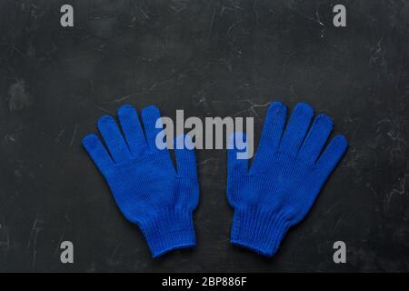 Blue working gloves over dark background, construction tools. Minimal black Stock Photo