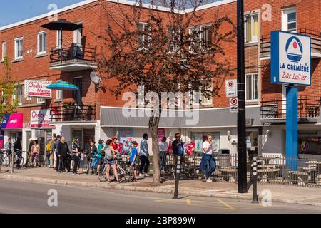 Montreal, CA - 17 May 2020: People in line to buy ice-cream during Coronavirus pandemic on Masson street. Stock Photo