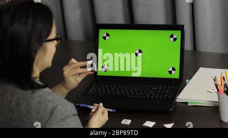 Woman teacher making online video call on laptop with green screen, chroma key. Distance education chat. Working from home with children online class. Kids coronavirus quarantine. Coach recording blog Stock Photo