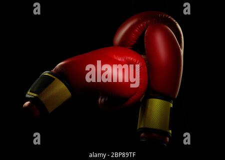 Boxers red gloves.. Professional sport equipment isolated on black studio background. Concept of sport, leadership, competition, healthy lifestyle in motion and action, training. Close up, copyspace. Stock Photo