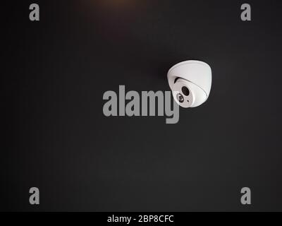CCTV system security on black background with copy space. Surveillance camera installed on dark ceiling to monitor for safety. Stock Photo