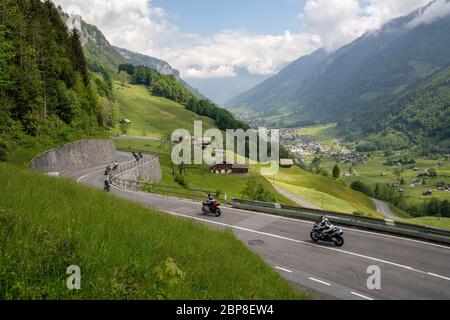 Linthtal, GL / Switzerland - 17 May 2020: A view of many motorcycles racing down the curvy Klausenpass mountain road in the Swiss Alps near Glarus Stock Photo