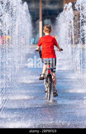 Boy, child on a bicycle riding between fountain at city park. Boy on bike in the street at Gorky Park in Moscow, Russia Stock Photo