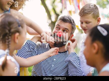 Man with small children on ground outdoors in garden in summer, playing. Stock Photo