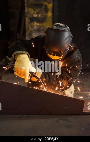 worker welding metal with sparks at factory Stock Photo