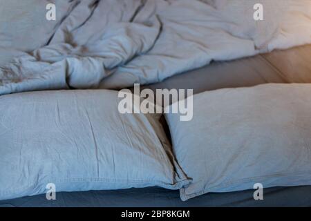Closeup of gray pillows and blankets with a sheet on the bed Stock Photo