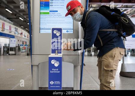 Commuters using hand sanitiser points at Waterloo Underground station during the coronavirus pandemic. May 2020 Stock Photo