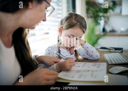 Mother and daughter learning indoors at home, Corona virus and quarantine concept. Stock Photo