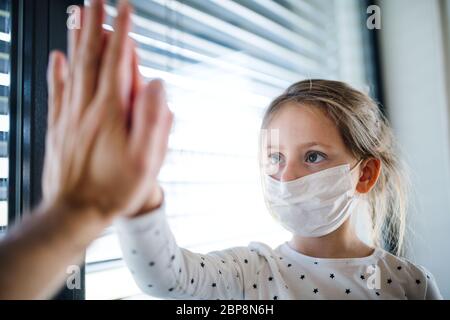 Small girl with unrecognizable mother indoors at home, giving high five. Stock Photo