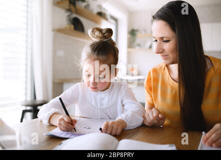 Mother and daughter learning indoors at home, Corona virus and quarantine concept. Stock Photo