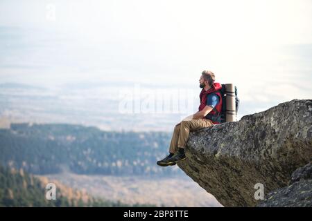 Mature man with backpack hiking in mountains in autumn, resting. Stock Photo