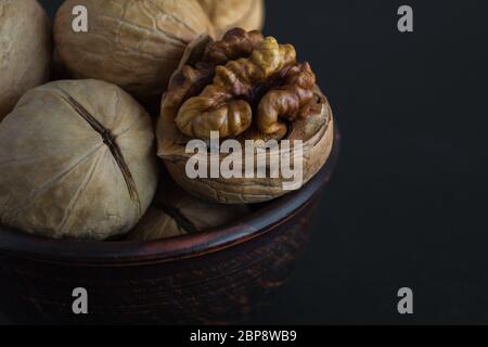 Walnuts in a plate on a black background. Closeup, selective focus on the walnut kernel. Useful snack. Healthy food. Space for text. Stock Photo