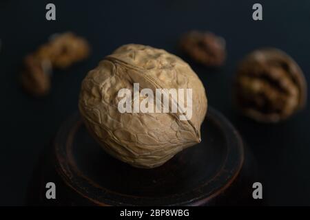 Walnut unpeeled in a saucer on a black background. A wholesome snack. Healthy food. Selective focus. Close-up. Space for text.