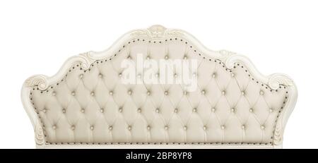 Shaped pastel beige color soft tufted leather capitone bed headboard of Chesterfield style sofa with carved wooden frame, isolated on white background Stock Photo