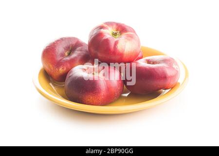 Ripe flat nectarines on plate isolated on white background. Stock Photo